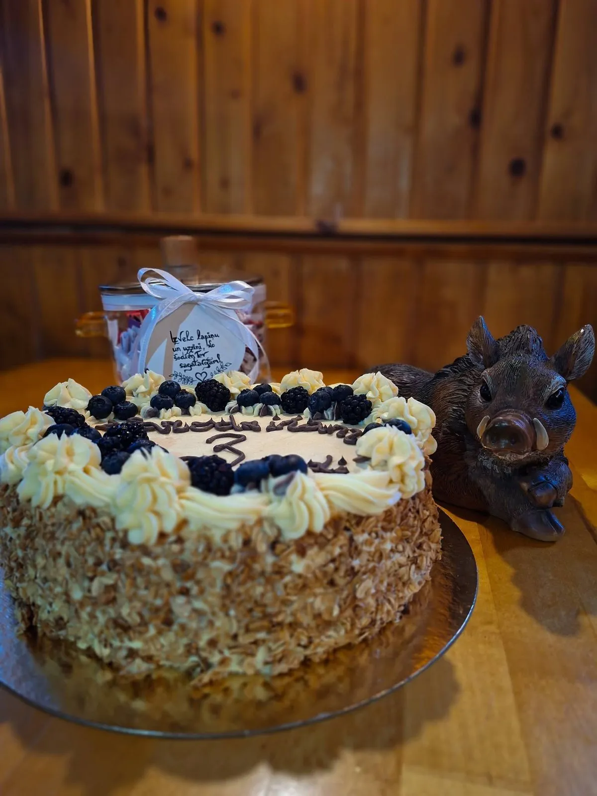 Torte ar ogām un krēmu uz koka galda, blakus kuiļa figūriņa